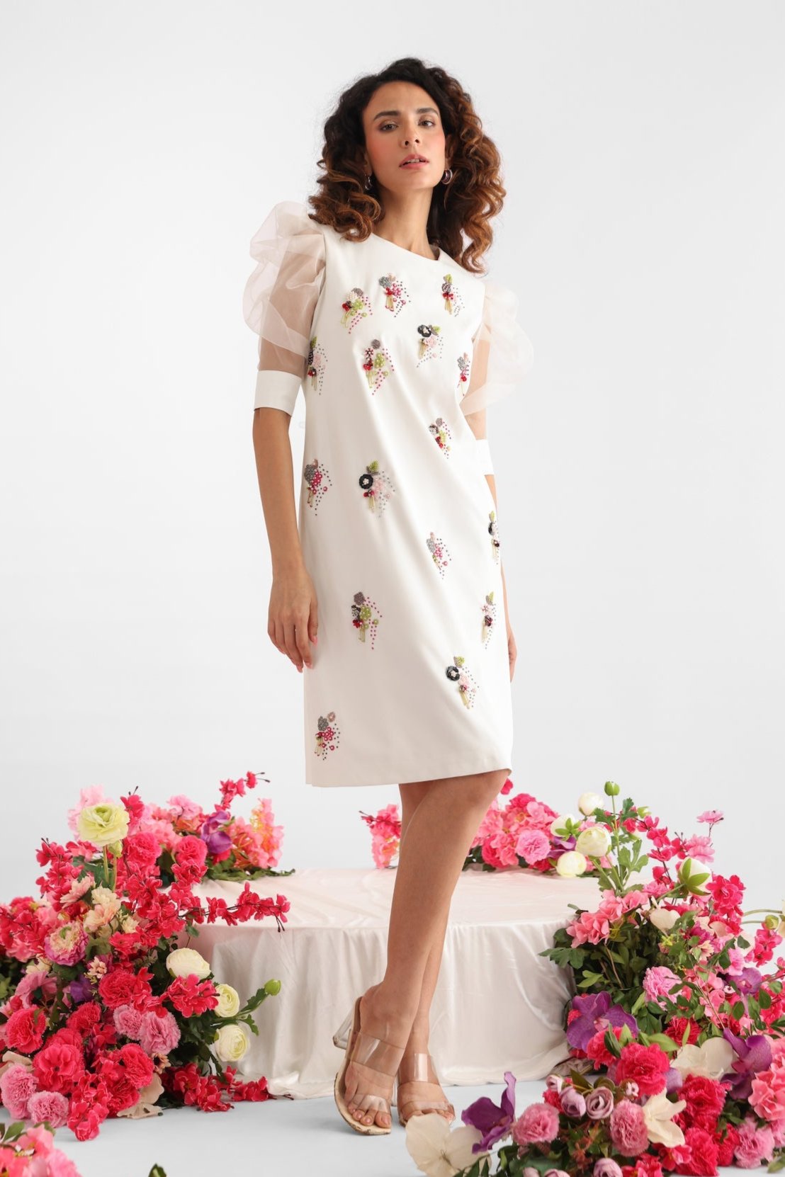 Golden Muslin white poly viscose shift dress with puff sleeves, vibrant floral embroidery, and whimsical tassel detailing.