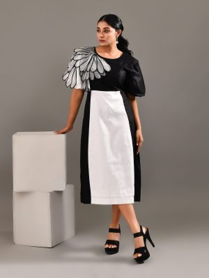 “Golden Muslin black and white cotton dress with exaggerated sculpted embroidered wing-inspired sleeves.”