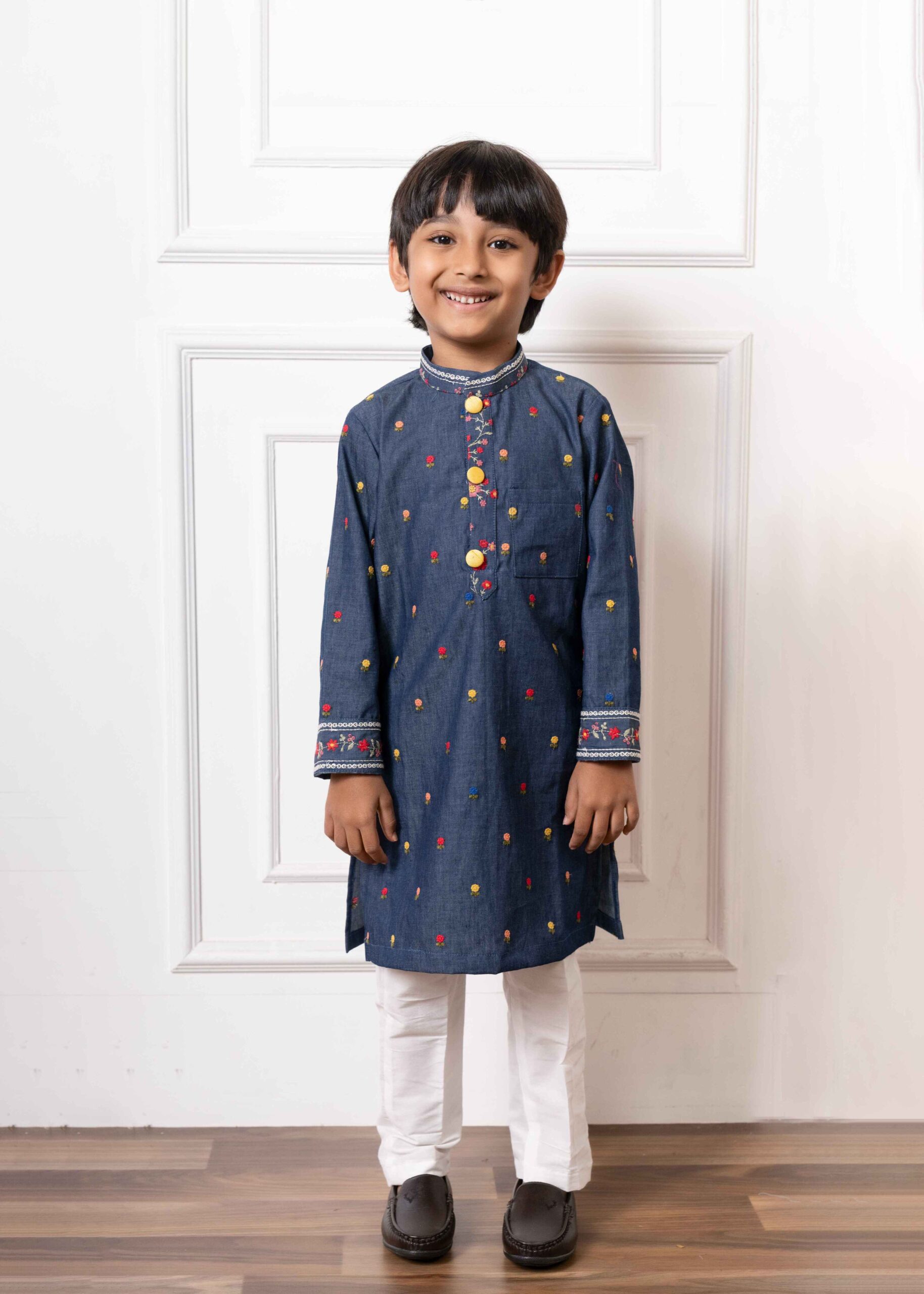 Deep blue denim kurta with multicolored floral embroidery, lace-trim mandarin collar, yellow buttons, and white straight-cut pants – Golden Muslin