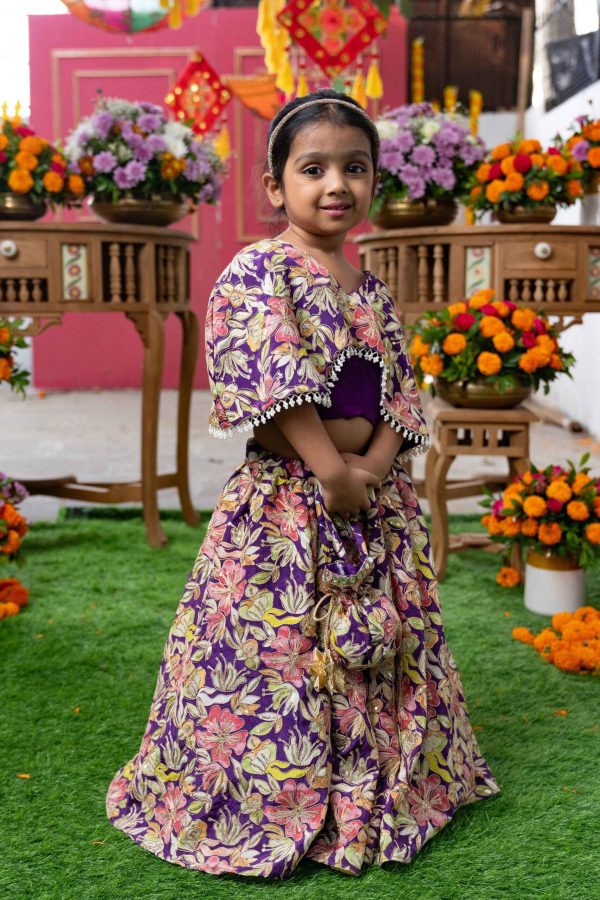 Purple crop top with attached embroidered cape, pearl tassel trims, flared floral embroidered lehenga, and matching potli bag – Golden Muslin