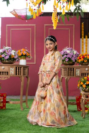 Golden-yellow tissue silk girls’ lehenga set with embroidered blouse, ikat-pattern lehenga, and matching potli bag – Golden Muslin