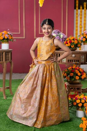 Mustard gold tissue silk girls’ lehenga set with embroidered asymmetrical blouse, beige-gold floral lehenga, and matching potli bag – Golden Muslin