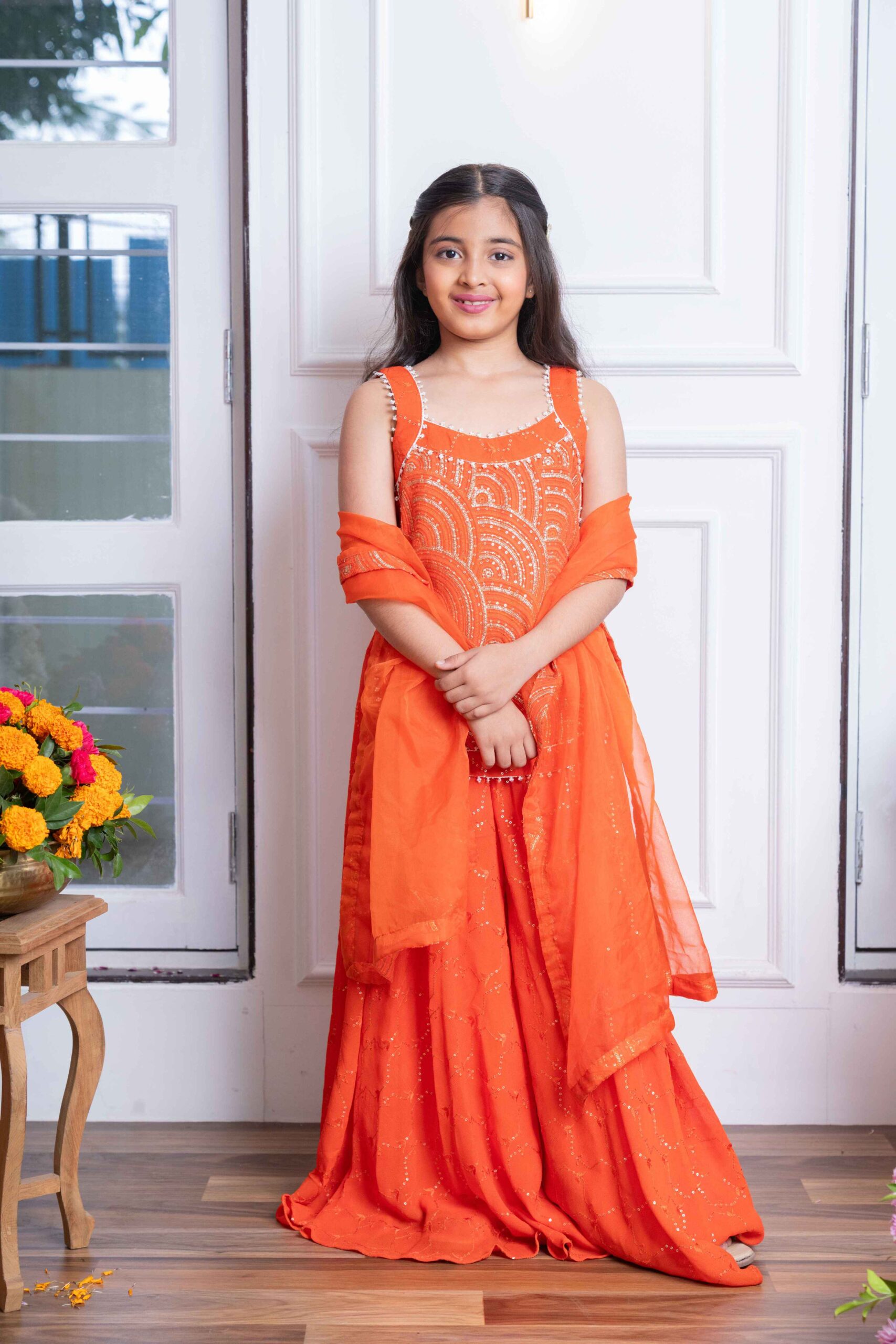 Orange girls’ sharara set with mirror-work crop kurti, flared sharara pants, and matching organza dupatta – Golden Muslin