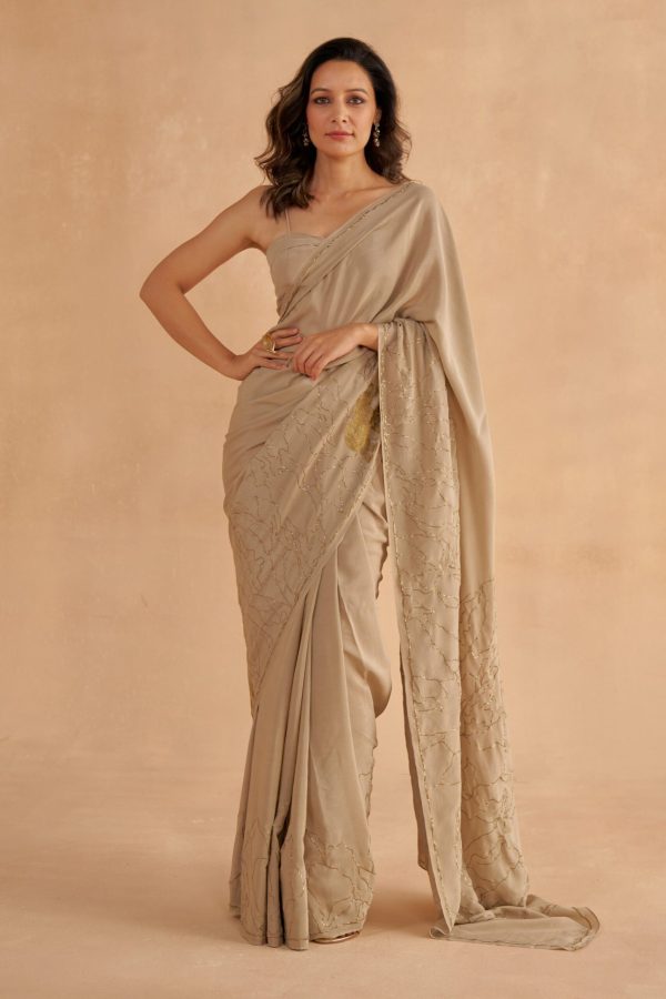 Golden Muslin warm grey fine crepe silk saree with Zardozi lotus and elephant embroidery, paired with a warm grey crepe silk sweetheart-neck blouse with golden detailing.