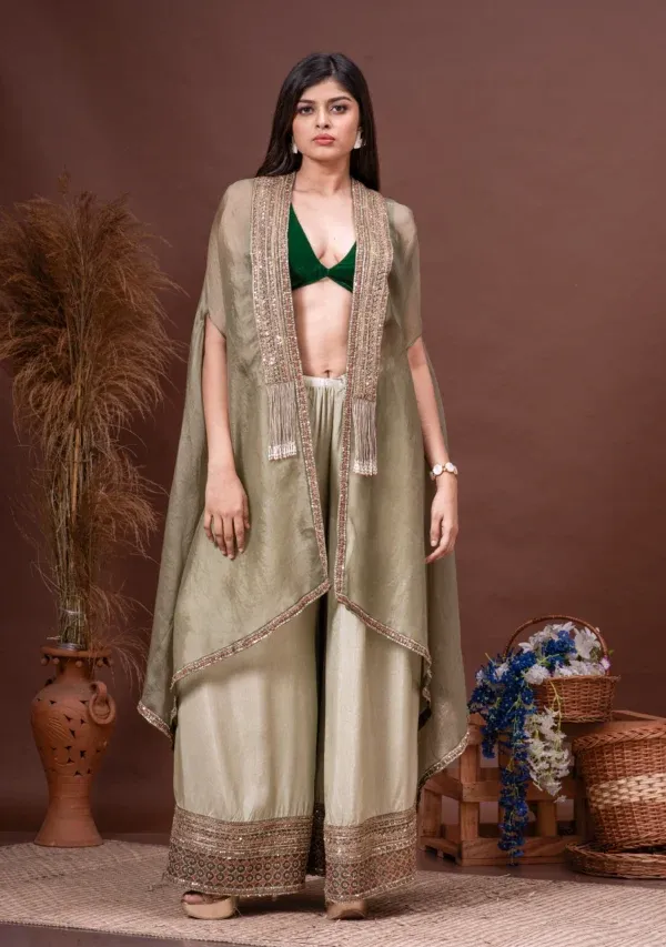 Model wearing a moss green silk organza cape with embroidered lace and tassels, paired with a bottle green bustier and palazzo pants from the house of Golden Muslin by Satya JB.