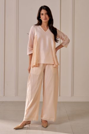 “Golden Muslin soft peach Chanderi top with V-neck and pleated crepe printed side panels, paired with matching crepe cotton wide-leg pleated pants.”