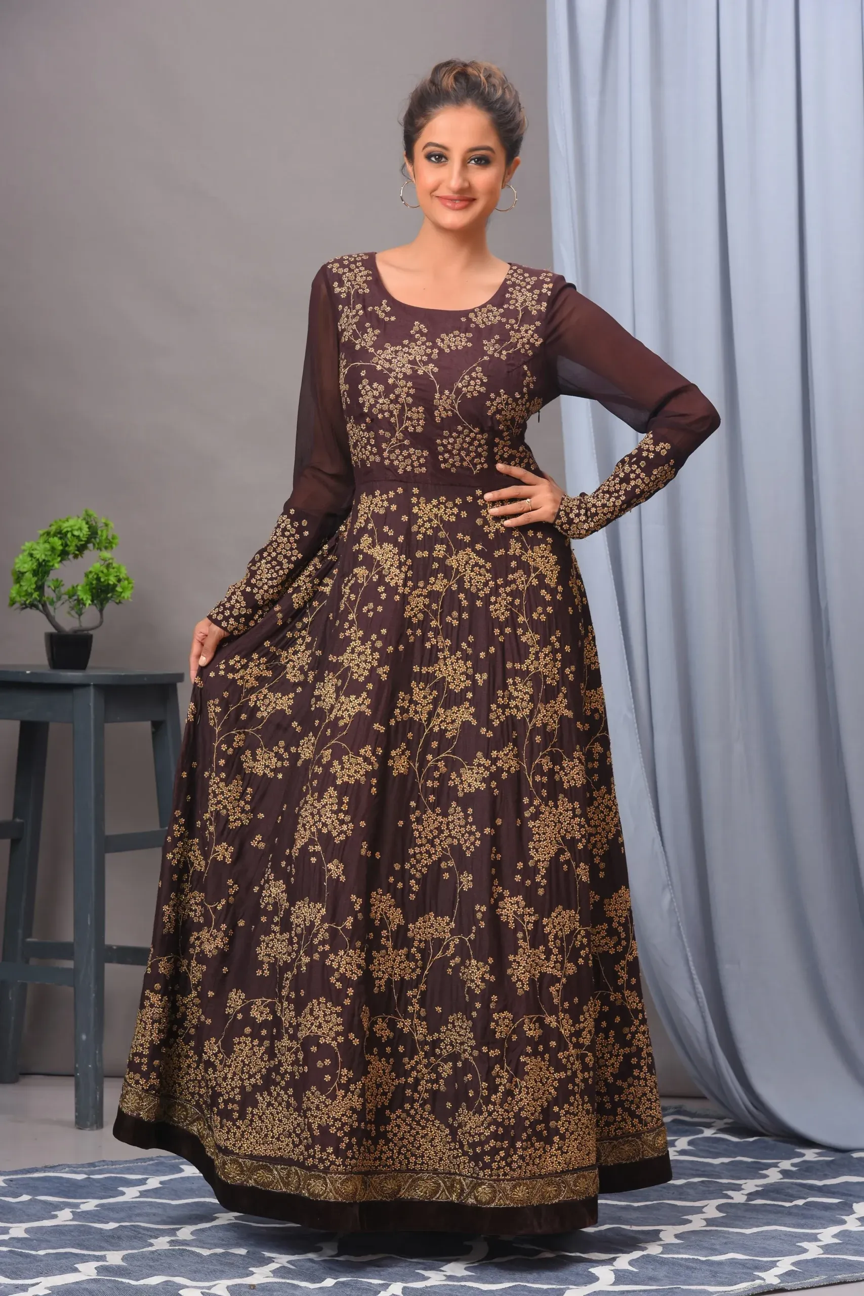 A coffee-colored Matka silk gown by Vivek Kumar from Golden Muslin, featuring intricate antique gold embroidery and a contemporary silhouette.