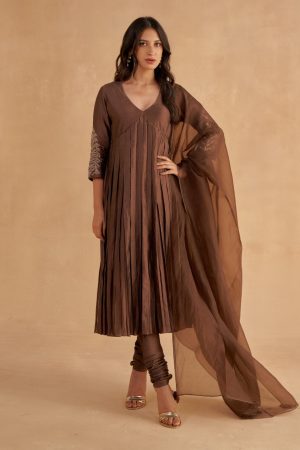 “Golden Muslin dark brown fine silk A-line V-neck kurta with Zardozi and Mukaish chintz-inspired sleeve embroidery, paired with fine silk churidar pants and brown organza dupatta with golden borders and tassels.”