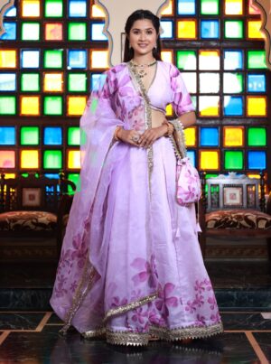 Lavender floral chanderi lehenga with V-neck blouse, organza dupatta, and matching potli from Golden Muslin by Priyanka Rathore.
