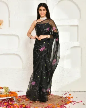 Black hand-painted organza saree with delicate floral motifs on a sheer, lightweight base, offering fluid drape and understated luxury for festive and evening wear, Golden Muslin by Priyanka Rathore.