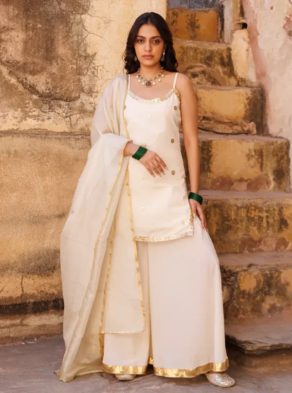 Ivory crepe sharara set with strappy kurta and delicate sequin lace detailing from Golden Muslin by Priyanka Rathore